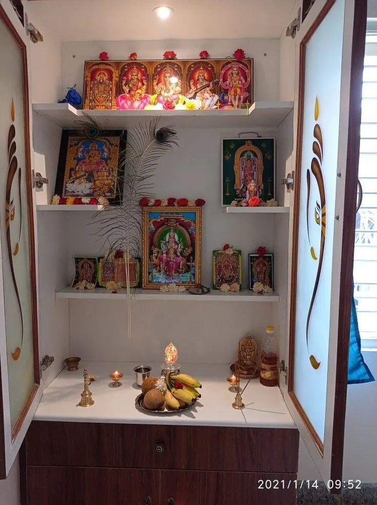 White and wood pooja mandir with framed deities on tiered shelves, finished at the workshop