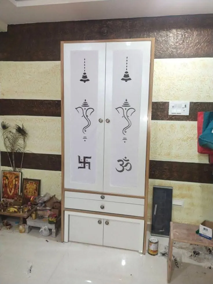 Installed pooja cupboard with frosted glass doors showing Om, Ganesha and swastika motifs