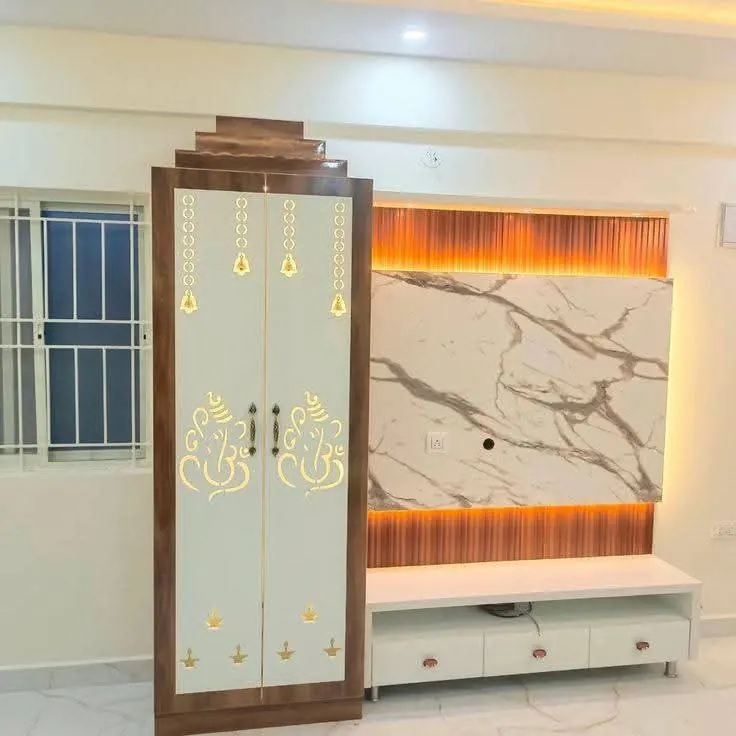 Pooja cabinet with golden Ganesha cut-outs beside a marble-pattern TV wall with warm LED lighting